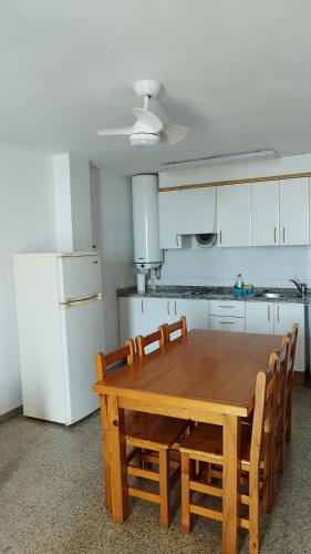 a kitchen with a wooden table and some white appliances at Apartaments El Sorrall in Blanes