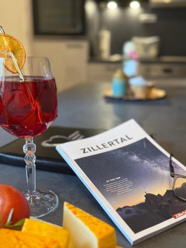 a book next to a glass of wine and a magazine at Restaurant Appartements Almdiele in Hart im Zillertal