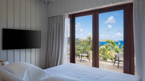 a bedroom with a bed and a balcony with a television at Exclusive Villa in a Privileged Place in Gustavia
