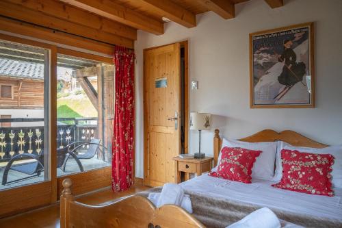 a bedroom with a bed with red pillows and a balcony at Chalet Elise des Alpes in Les Gets