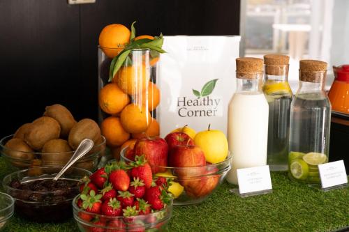 a table topped with bowls of fruit and bottles of milk at Hotel Dei Principati in Baronissi