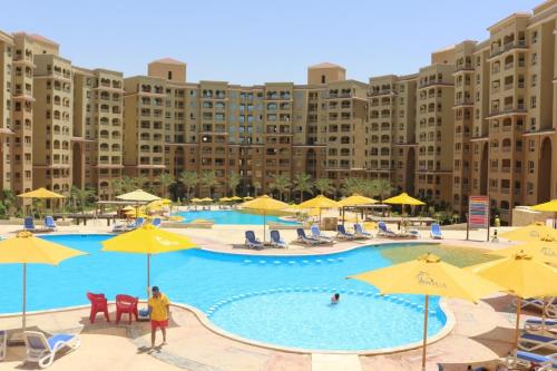 a large swimming pool with yellow umbrellas and chairs at قريه اكوا فيو الساحل الشمالى in El Alamein