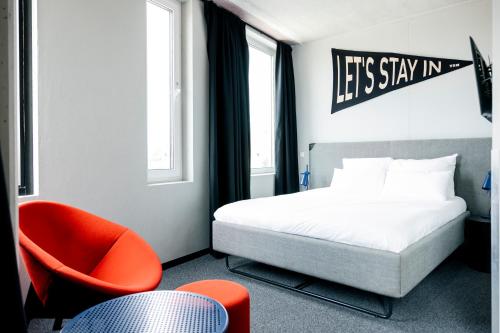 a hotel room with a bed and a chair at The Social Hub Delft Extended Stay in Delft