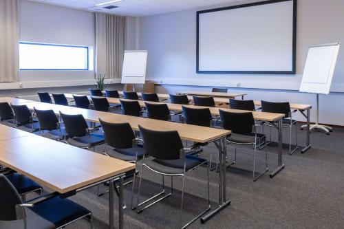 a classroom with tables and chairs and a projection screen at Scandic Helsinki Aviacongress in Vantaa