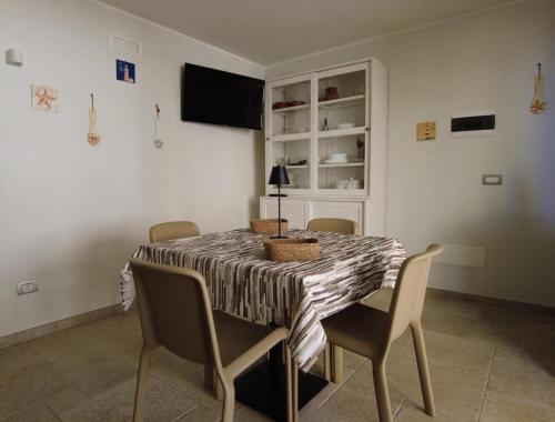Un comedor con una mesa con sillas y un televisor. en Dimora D'Altomare, en Mola di Bari