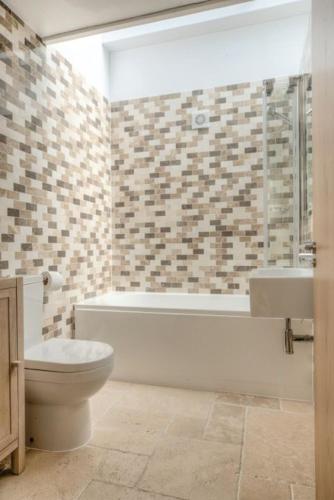 a bathroom with a toilet and a tub and a sink at House 2 in Looe