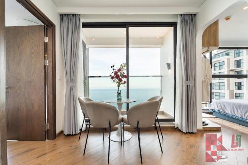 a bedroom with a table and chairs in front of a window at Apec Mandala Mui Ne by LHG - Sea View, Infinity Pool, Alacarte, 17m to Bàu Trắng Bình Thuận in Mui Ne