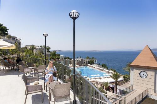 a woman sitting on a balcony next to a swimming pool at Duja Bodrum in Torba