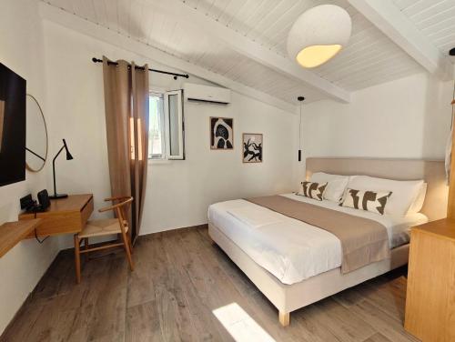 a bedroom with a white bed and a desk and a bed at Paxos Dream House in Vlachopoulátika