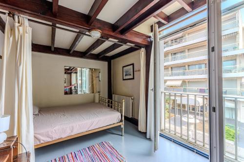 une chambre avec un lit et une grande fenêtre dans l'établissement Loft familial Arcachon, à Arcachon
