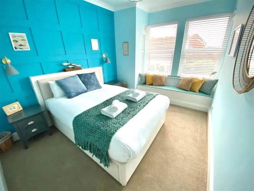 a blue bedroom with a bed and a window at 2 Bedroom Apartment with Garden, Close to Beach in Southend-on-Sea
