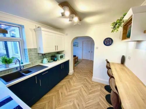 a kitchen with black cabinets and a wooden table at 2 Bedroom Apartment with Garden, Close to Beach in Southend-on-Sea
