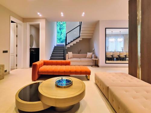 a living room with orange furniture and a staircase at Villa Takiana - 4BHK pvt pool, Gym, 5mins to beach in Anjuna