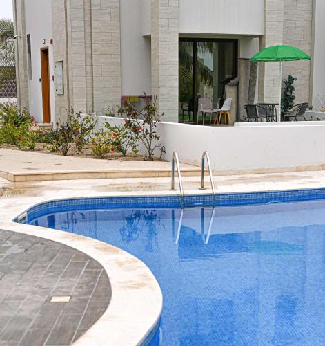 a swimming pool in a house with an umbrella at استيديو هوانا صلاله Hawana Salalah studio in Wādī Khasbar