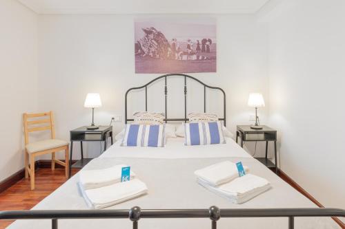 a bedroom with a bed with two tables and a chair at Taosa - baskeyrentals in Zumaia