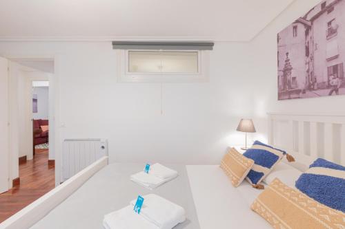 a white living room with a white couch and blue pillows at Taosa - baskeyrentals in Zumaia