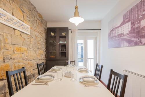 a dining room table with chairs and a stone wall at Taosa - baskeyrentals in Zumaia