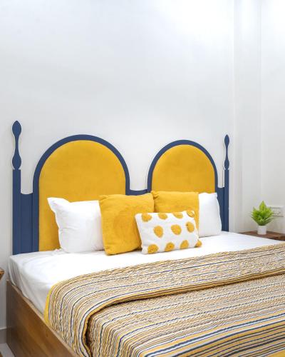 a bedroom with a large bed with yellow pillows at Thamosa Stays in Jaipur