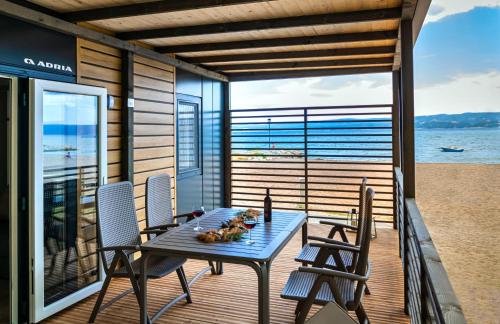 a table and chairs on a deck with a view of the ocean at Camping Almissa in Omiš