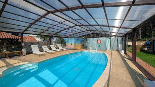a swimming pool with a retractable pergola over it at Cabañas de Lires in Lires