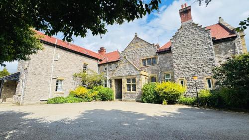an old stone house with a driveway in front of it at Berthlwyd Country House in Conwy