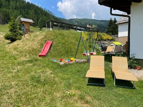 a backyard with two chairs and a swing and a playground at Nockalm Cottage in Bad Kleinkirchheim