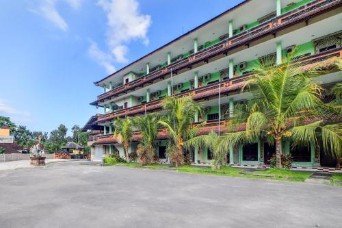 a large building with palm trees in front of it at Collection O Bali near Terminal Ubung formerly Batukaru Garden Hotel in Kesiman