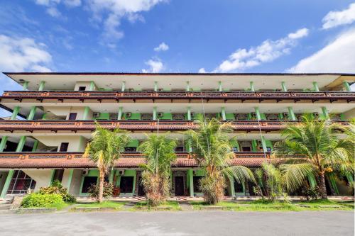 a building with palm trees in front of it at Collection O Bali near Terminal Ubung formerly Batukaru Garden Hotel in Kesiman