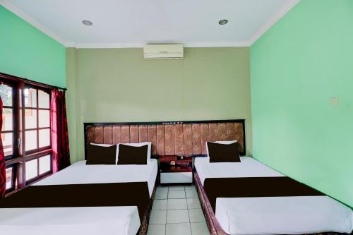 a room with two beds and a window at Collection O Bali near Terminal Ubung formerly Batukaru Garden Hotel in Kesiman