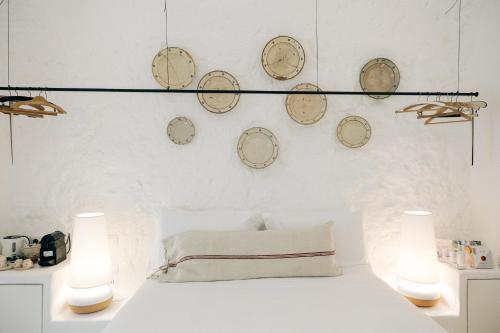 a bedroom with a white bed with clocks on the wall at Corte Manfredi in Alessano