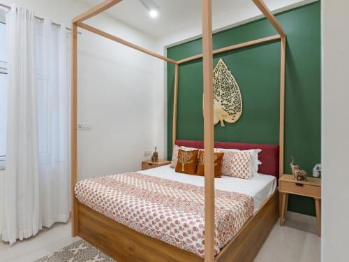 a bedroom with a four poster bed with green walls at Thamosa Stays in Jaipur
