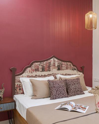 a bedroom with a bed with a red wall at Thamosa Stays in Jaipur