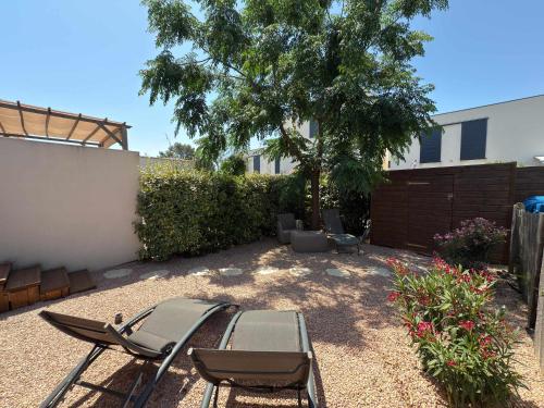un patio avec des chaises, une table et un arbre dans l'établissement Villa moderne et familliale dans une résidence à 500m de la plage, à Sérignan