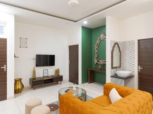 a living room with a orange couch and a television at Thamosa Stays in Jaipur