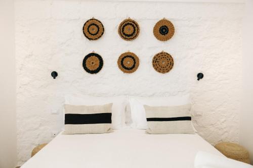 a bedroom with a white wall with a bed with pillows at Corte Manfredi in Alessano