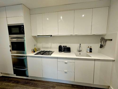 a kitchen with white cabinets and a sink at River View in Tonbridge
