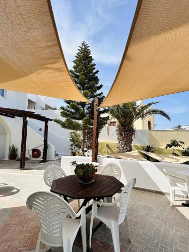 a patio with a wooden table and white chairs at Arlene Suites in Mesaria