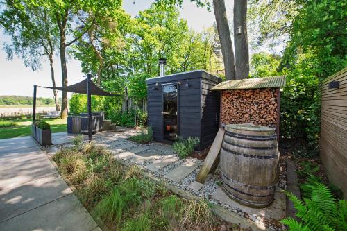a small shed with a barrel next to a sidewalk at 86, Bed & Outdoor Wellness - Sauna, Hottub, Icebath & Outdoor Shower included! in Oisterwijk