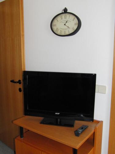 a television on a table with a clock on the wall at HappyLivingApartments in Villach