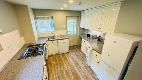 a large kitchen with white appliances and wooden floors at Berthlwyd Country House in Conwy