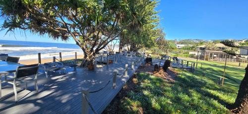 a row of tables and chairs next to the beach at Private Suite Nautilus Beach Front Resort in Coffs Harbour
