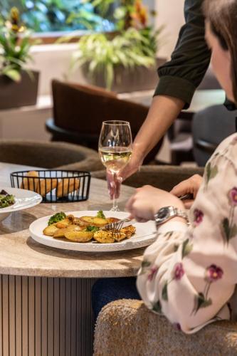 a table with a plate of food and a glass of wine at The Y Hotel in Athens