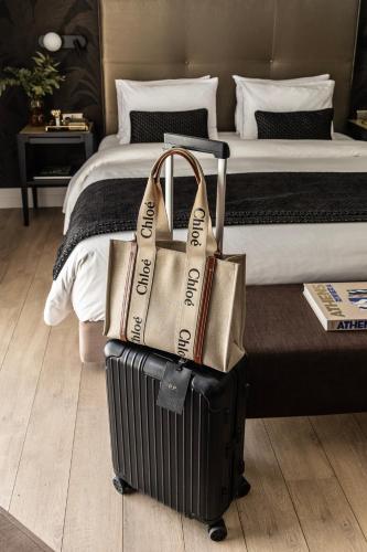 a pile of luggage sitting next to a bed at The Y Hotel in Athens