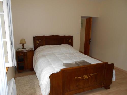 a bedroom with a wooden bed and a night stand at Maison de campagne rustique et confortable in Mazières-en-Gâtine