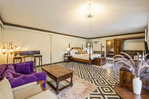 a living room with a purple couch and a bed at The Kablan Luxury Living Ranthambore in Sawāi Mādhopur