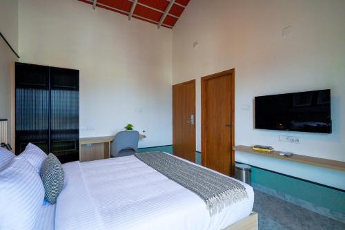 a bedroom with a bed and a flat screen tv at Olive Hotel Chikkamagalur by Embassy Group in Jāmb