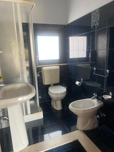 a bathroom with a white toilet and a sink at Casa Artemisia in Marzamemi