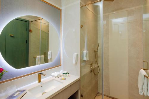 a bathroom with a shower and a sink and a mirror at The Tivoli New Delhi in New Delhi