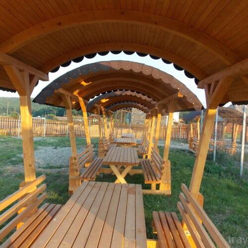 a wooden gazebo with benches sitting under it at Căsuțe Suzanne Băile Figa-cu aer conditionat in Beclean