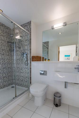 a bathroom with a toilet and a glass shower at House 28 in Looe